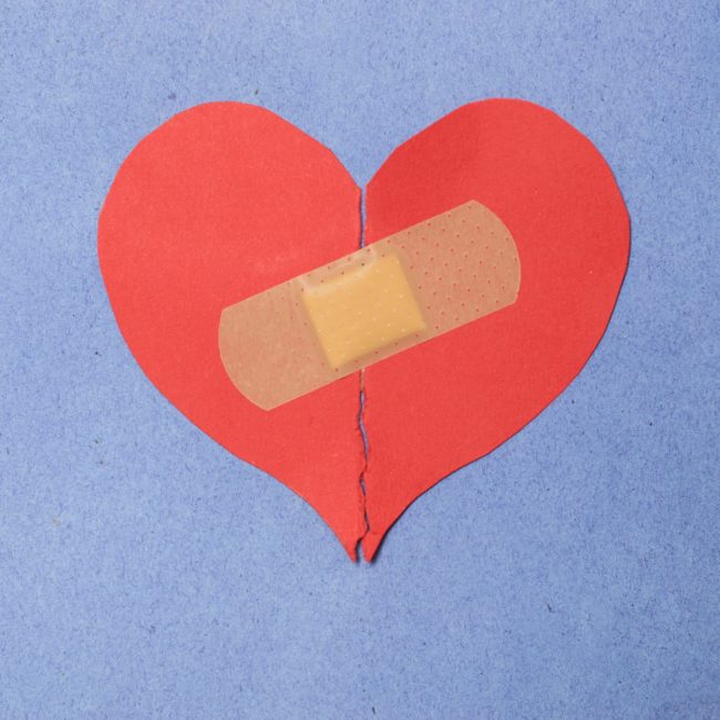 Abstract concept of love. Broken paper heart with medical health patch.